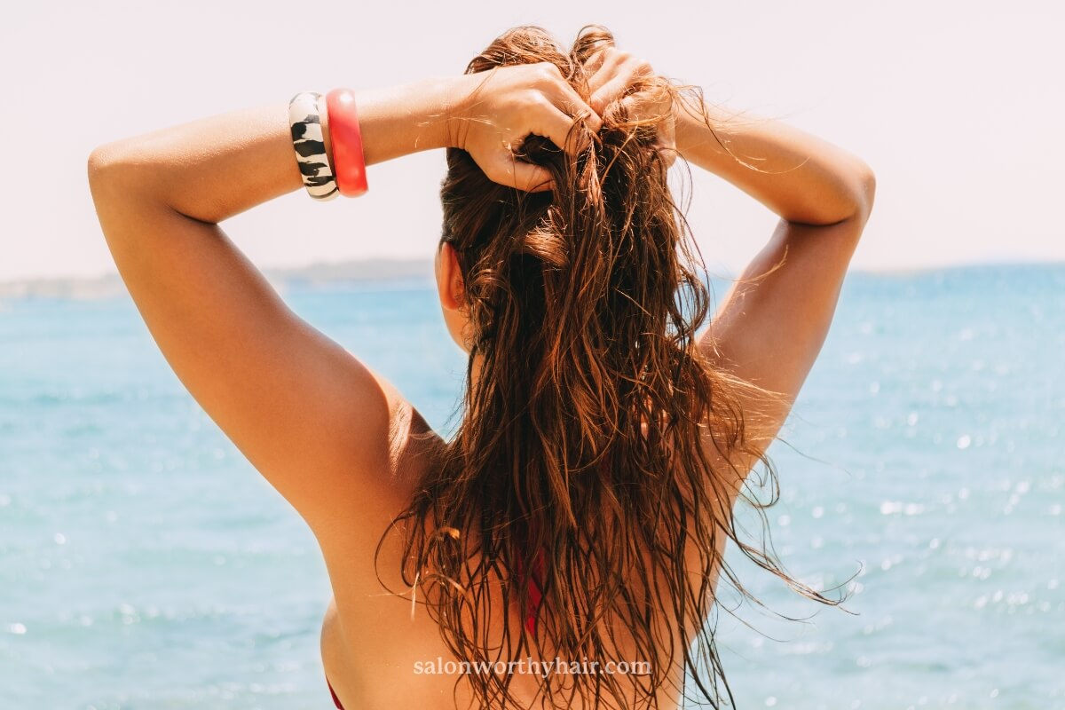 A woman with naturally greasy hair standing in the ocean with salt water up to her waist